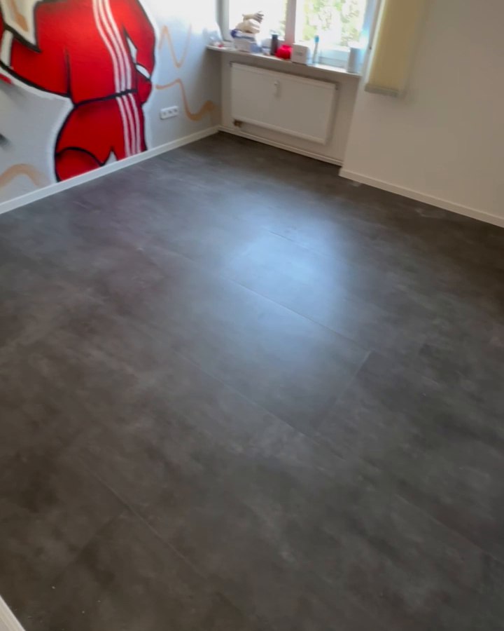 Fertiger grauer Designboden mit weißen Sockelleisten im selben Raum.